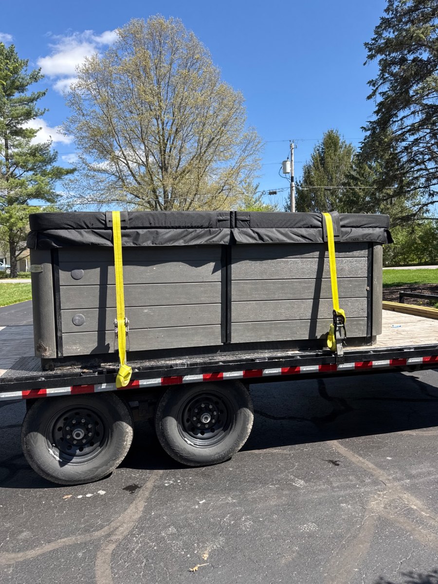 Grey hot tub strapped down head-on on our flatbed trailer, ready to move