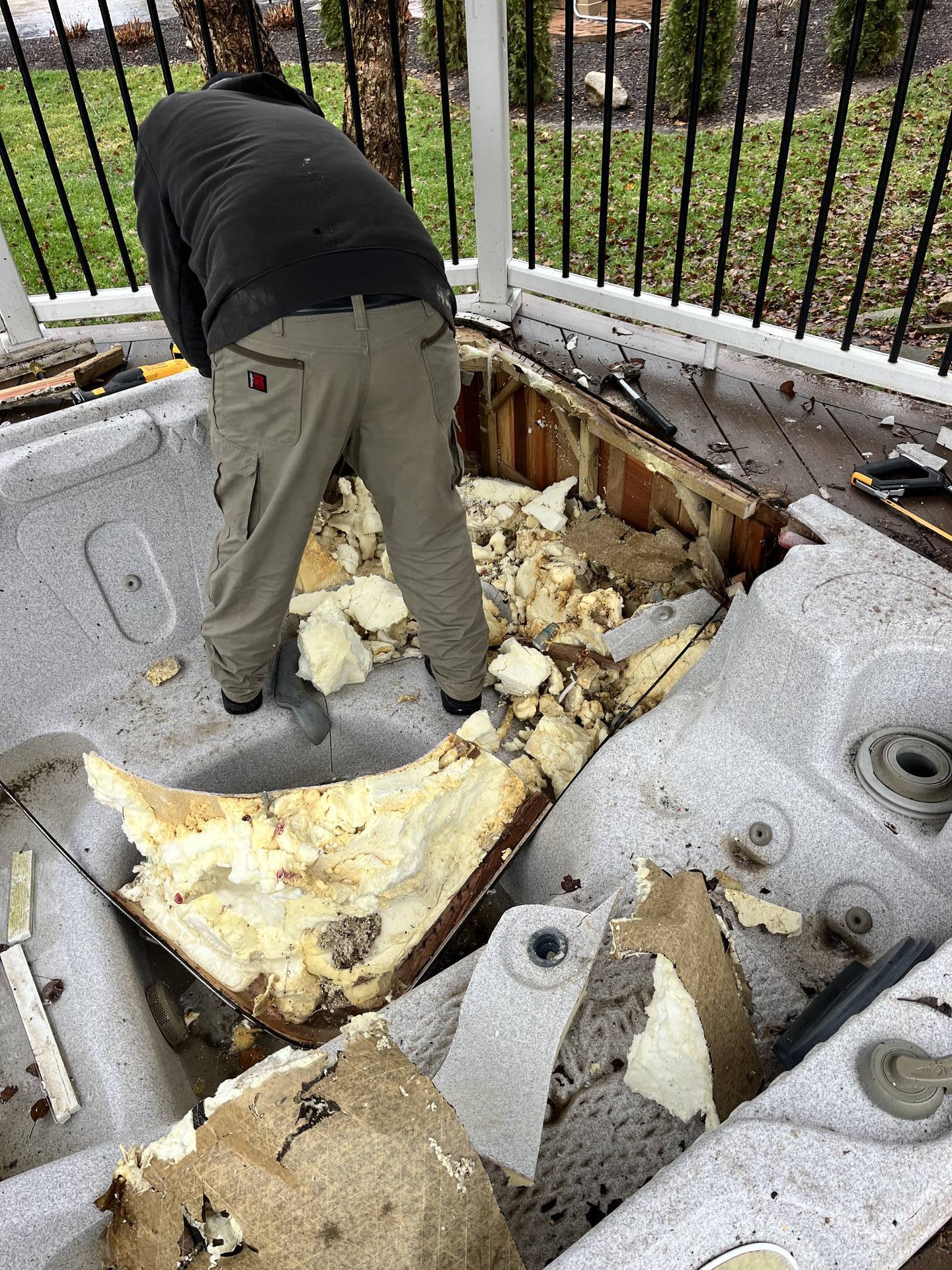 Crew member cutting apart an old hot tub on a deck