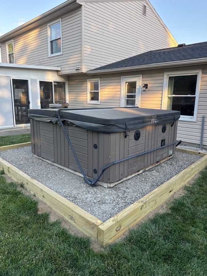 Customer photo of a hot tub sitting on its gravel pad behind a house